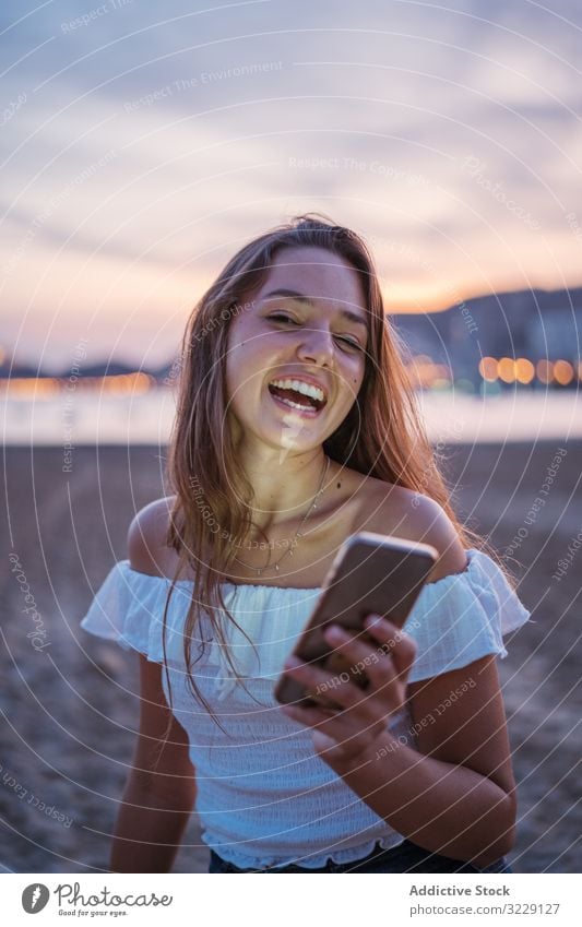 Fröhliche junge Frau benutzt Smartphone im Urlaubsort Strand benutzend soziale Netzwerke Lächeln Resort Abend Sommer Browsen Gerät Apparatur Mobile Telefon