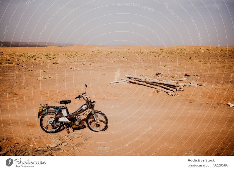 Motorrad und Baumstämme in der Wüste wüst reisen Sand Totholz Holz Haufen Marokko Afrika geparkt Verkehr Fahrzeug Ausflug Reise trocken trocknen Dürre Himmel