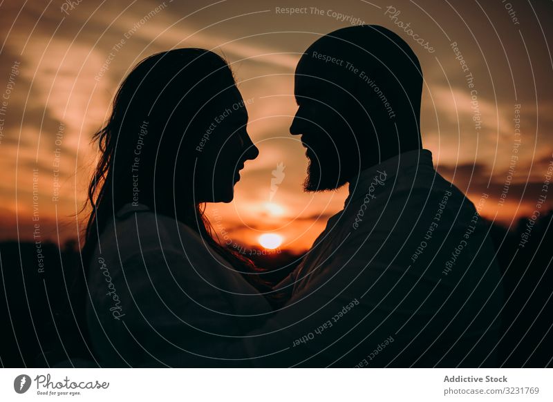 Liebendes Paar umarmt sich, während es am untergehenden Himmel steht Silhouette Sonnenuntergang schließen Angebot Feld Landschaft Dämmerung Valentinsgruß