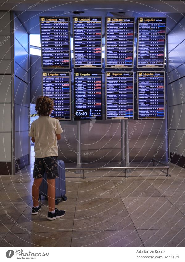 Leseprogramm für Kinder in der Halle des Flughafens Junge Koffer Anzeigetafel Aussehen lesen Zeitplan Saal Portugal reisen Tourist Gepäck Abheben Ankunft