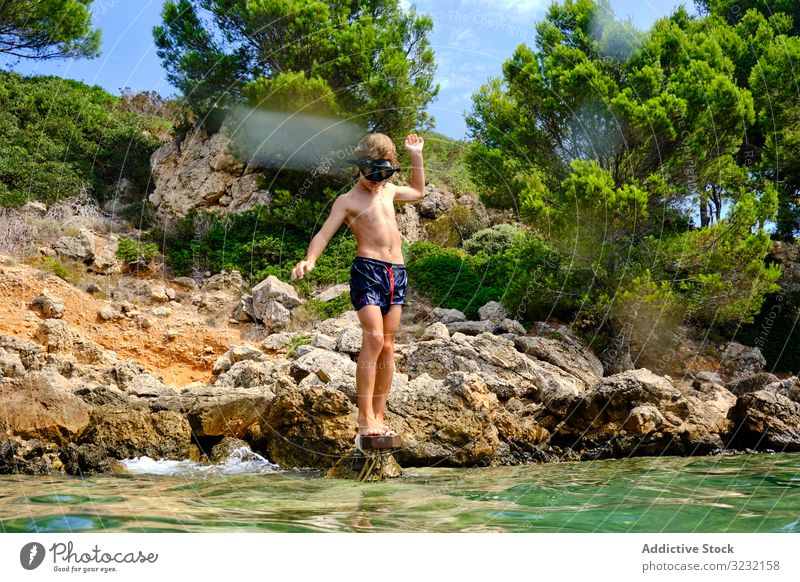 Kleiner Junge macht sich bereit, ins Wasser zu springen MEER Sinkflug Sommer Meeresufer Gleichgewicht Kind Mundschutz Küste reisen aktiv felsig Tourismus Klippe