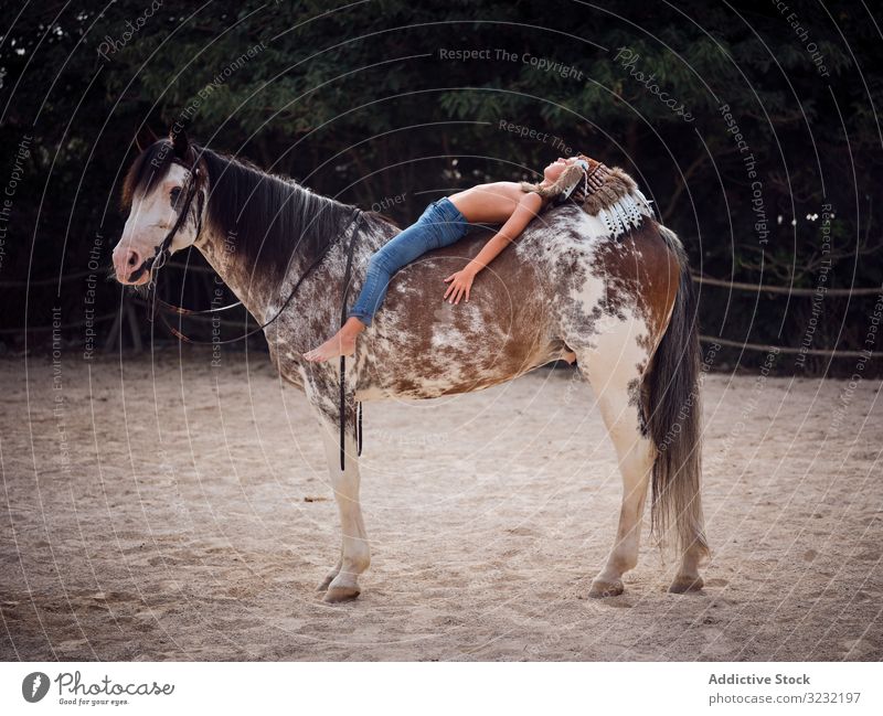 Friedliche Tagträume eines Kindes im Liegen auf einem Pferd Junge Harmonie authentisch Lügen Kriegsmütze Pferderücken Liebe Art Inder Tracht Wachtraum