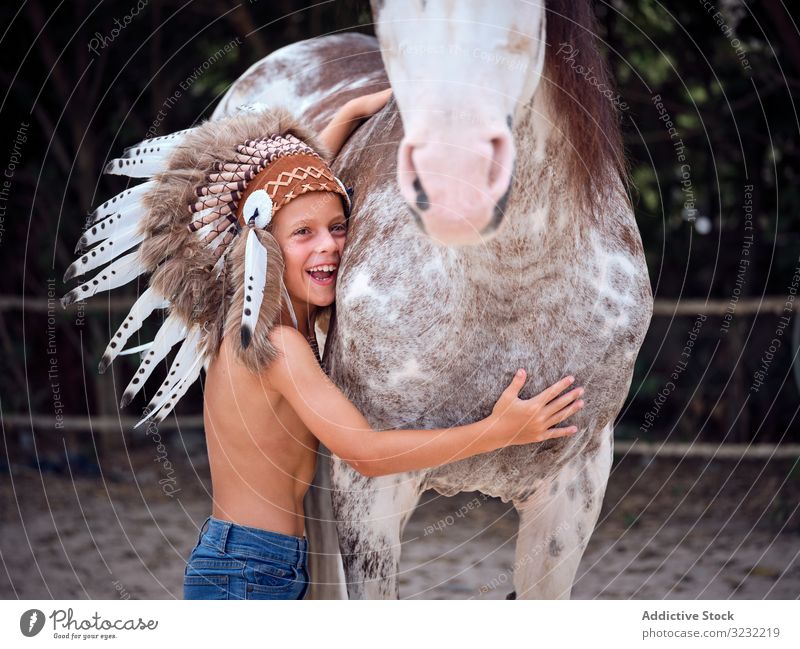 Zarter Junge umarmt Pferd auf dem Bauernhof Bonden Kind Angebot authentisch Harmonie Kriegsmütze Art Hengst Inder Liebe berühren Tracht Streicheln konzentriert