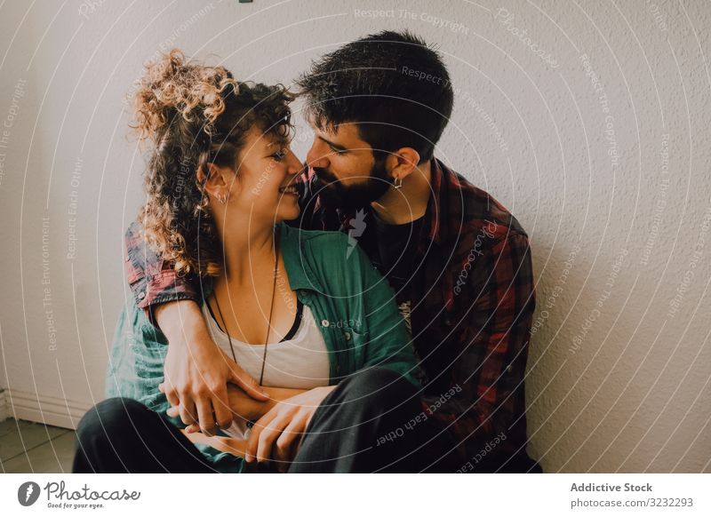 Glückliches Paar umarmt sich zu Hause an der Wand Umarmen heimwärts freudig Lächeln lässig Umarmung Hipster modern Angebot Zuneigung Liebhaber Partnerschaft