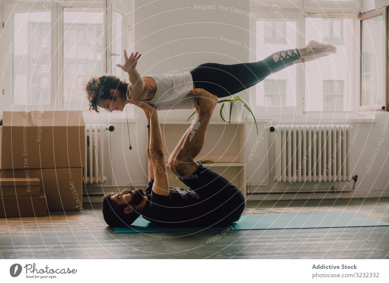 Hipster-Paar, das zu Hause gemeinsam Yoga praktiziert acroyoga Gleichgewicht Zusammensein heimwärts sportlich Übung Stock modern Appartement Vertrauen Sport
