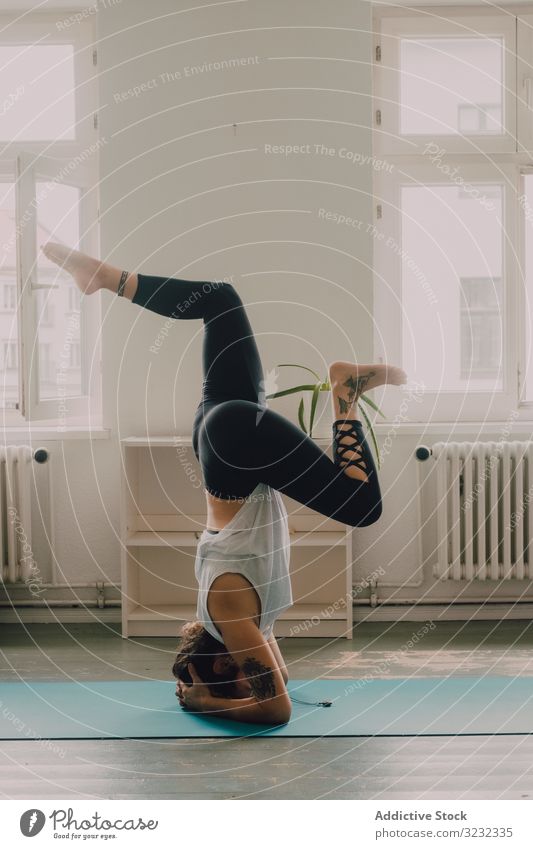 Fitte Frau, die zu Hause Yoga-Pose praktiziert und auf dem Kopf steht üben positionieren Kopfstand heimwärts Sportkleidung passen Asana Übung Stock Appartement