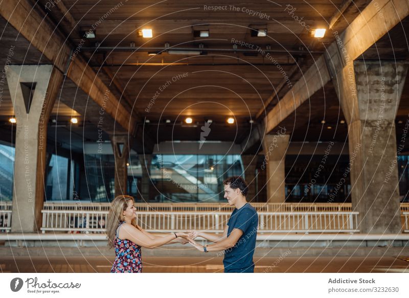 Frau und Mann fassen sich unter einer großen Stadtbrücke an den Händen Paar Spaß haben reisen Architektur Brücke urban Urlaub umklammernd Partnerschaft