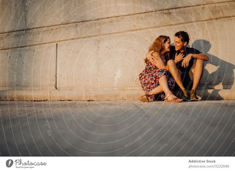 Mann und Frau sitzen und umarmen sich an der nahe gelegenen Straßenmauer Paar Spaß heiter aufgeregt spielerisch Wand Menschen verrückt gelungen Inhalt freudig