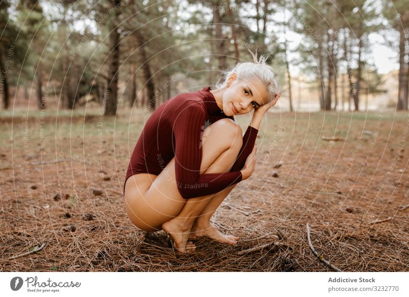 Schöne moderne Frau ruht barfuss in immergrünem Wald Wälder Harmonie hockend primitiv umarmende Knie blond sorgenfrei Barfuß attraktiv schön charmant ruhen