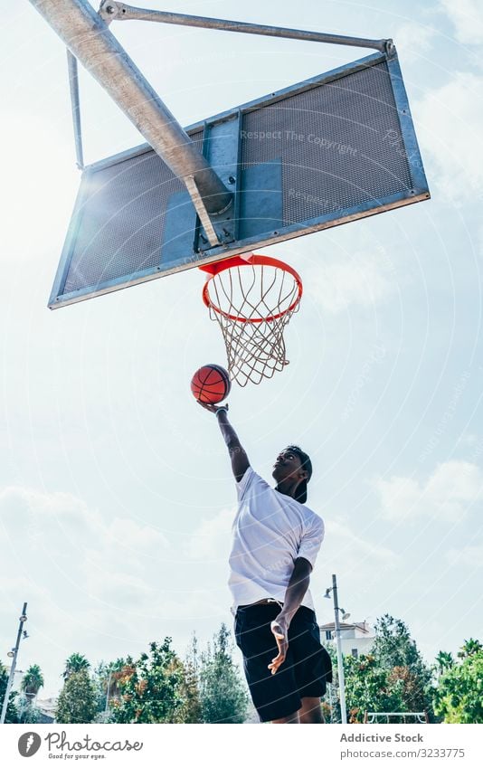 Afroamerikanischer Sportler hängt auf Basketball-Runde Ball tretend Netz Slam Dunk Spiel Spieler Stadion Spielen Sportbekleidung Aktivität Feld männlich