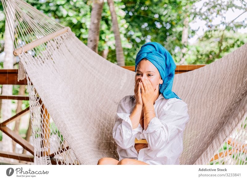 Frau mit Turban ruht sich in Hängematte aus ruhen Glück Lächeln berührendes Gesicht sitzen Terrasse Baum Grün Hemd friedlich Costa Rica jung