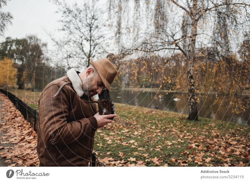 Männlicher Fotograf steht im Herbstpark Mann Fotoapparat retro Park London lässig friedlich Erwachsener männlich Großbritannien England altehrwürdig Blatt