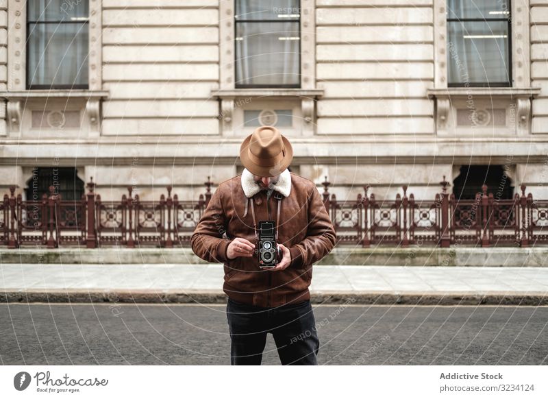 Männlicher Tourist geht in der Nähe eines alten Gebäudes spazieren Fotoapparat Straße retro Fotograf Mann London England stehen männlich Erwachsener Großstadt