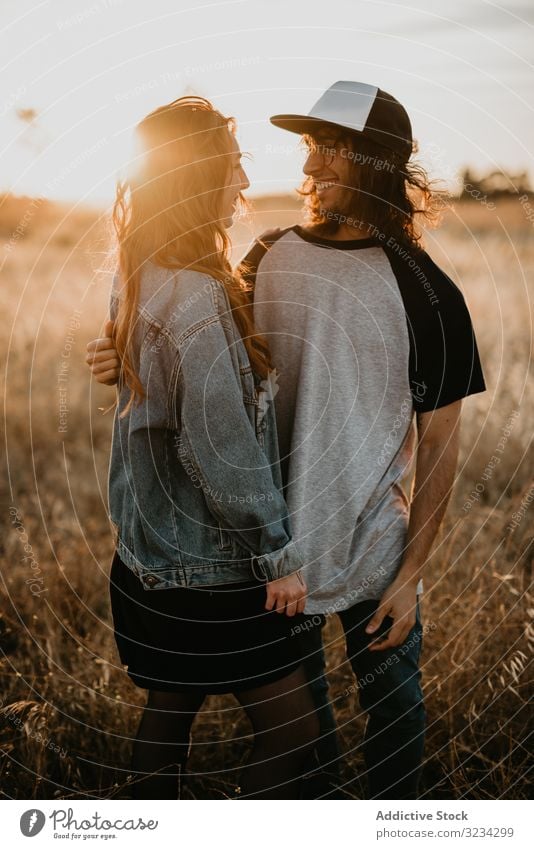 Hipster-Teenager-Paar, das sich auf dem Feld im Sonnenlicht verbindet ländlich Bonden Umarmen Sonnenuntergang Partnerschaft Sommer Generation romantisch