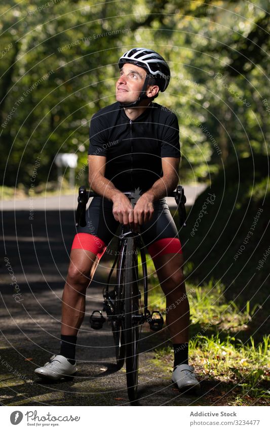 Profi-Radfahrer fährt Fahrrad im Park Mitfahrgelegenheit Sportler Rennen professionell Weg sonnig tagsüber männlich Sicherheit Schutz Schutzhelm Schutzbrille