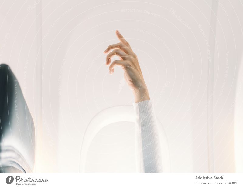 Person in weißem Pullover hebt die Hand im Flugzeug Ebene Licht Salon Fliege Aufmerksamkeit Erhöhung Fluggerät Ausdruck reisen Erwachsener Konzept Windstille