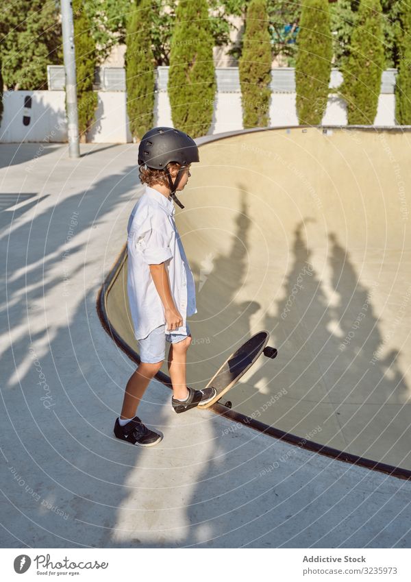 Kind mit Helm beim Skateboardfahren Skatepark Rampe Mitfahrgelegenheit Schutzhelm Sonnenlicht Sport Freizeit Hobby Junge jung anhaben Kindheit Sommer sonnig