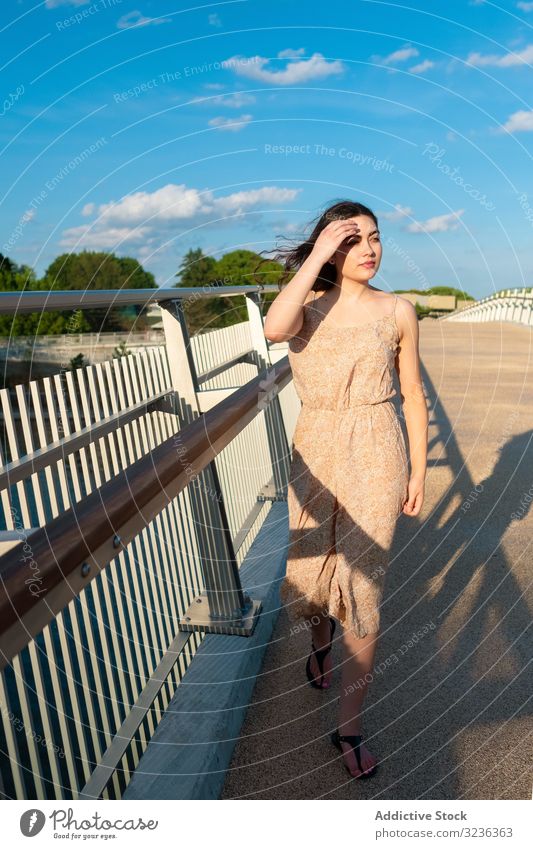 Friedliche Frau in Tracht geht über eine ländliche Brücke Spaziergang friedlich entspannt verträumt Sonnenkleid sonnig Wind schlendern Blauer Himmel