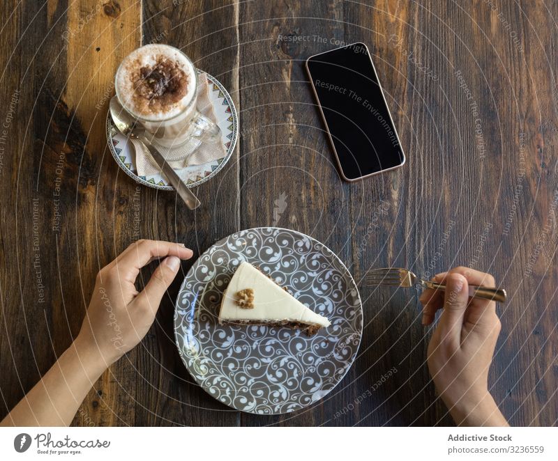 Frau isst Kuchen im Restaurant Kaffee Tisch Smartphone Tasse süß Café Dessert lecker Getränk Spielfigur essen geschmackvoll Freizeit hölzern trinken blanko