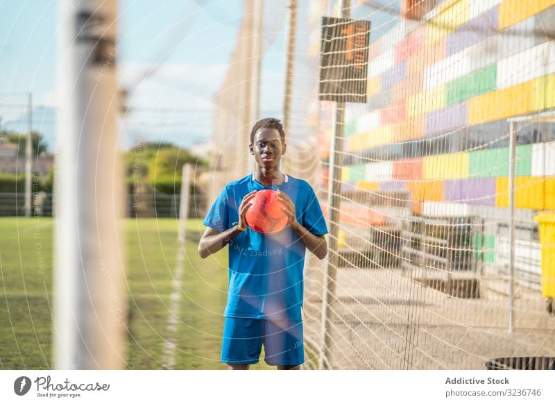 Schwarzer Teenager auf Fussballplatz Fußball Feld Netz Ball Training Sportbekleidung ethnisch Gras männlich Jugendlicher Rasen sonnig tagsüber schwarz