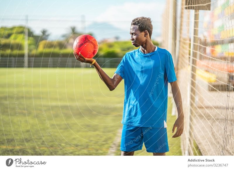 Schwarzer Teenager auf Fussballplatz Fußball Feld fettarm Netz Ball Training Sportbekleidung ethnisch Gras männlich Jugendlicher Rasen sonnig tagsüber schwarz