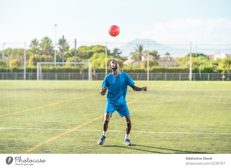 Dünner schwarzer Teenager jongliert Fussball auf dem Kopf Fußball Ball jonglieren Feld Training Spieler Sportbekleidung ethnisch Gras männlich Jugendlicher