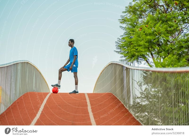 Ethnischer Fussballspieler steht auf dem Weg Fußball Training Ball Straße Teenager ethnisch Spiel Errungenschaft Triumph schwarz Afroamerikaner wettbewerbsfähig