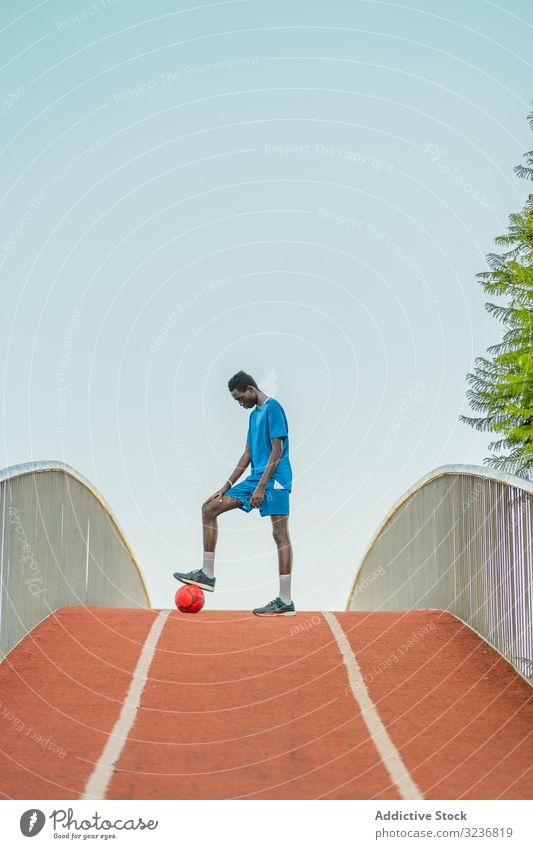 Ethnischer Fussballspieler steht auf dem Weg Fußball Training Ball Straße Teenager ethnisch Spiel Errungenschaft Triumph schwarz Afroamerikaner Sieg
