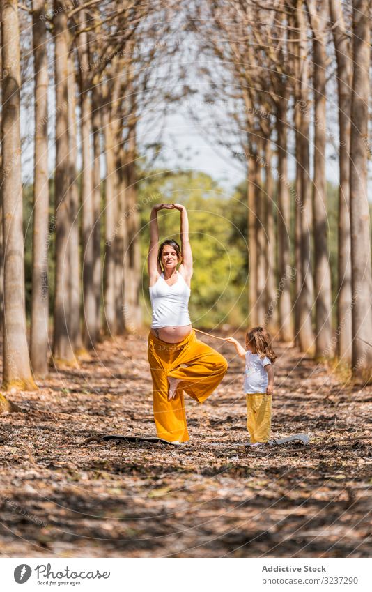 Fröhliche Mutter und Tochter praktizieren bei Sonnenschein Yoga im Park heiter Dehnung Waldwiese sich[Akk] entspannen Spaß üben Übung Lachen Harmonie Pose