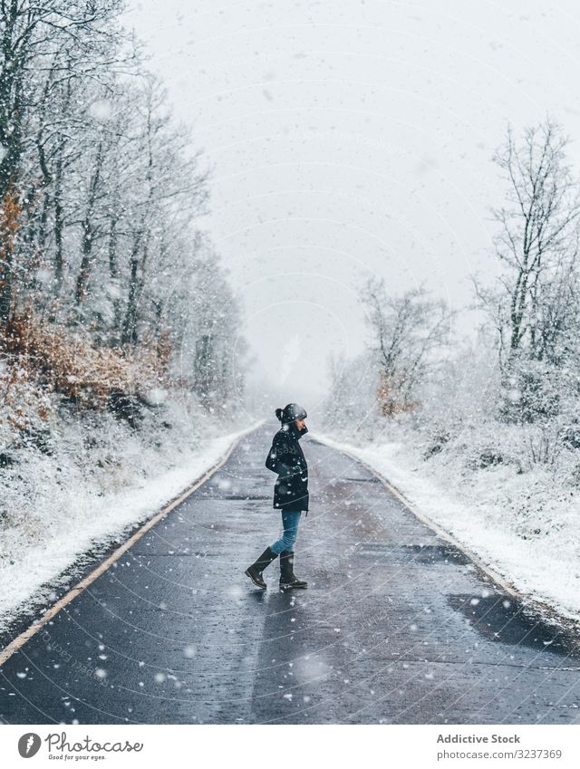 Junge Frau überquert Winterlandstraße Straße Schnee Land neblig wolkig trist Wald Spaziergang jung allein durchkreuzen einsam Baum gefroren kalt Natur Erholung
