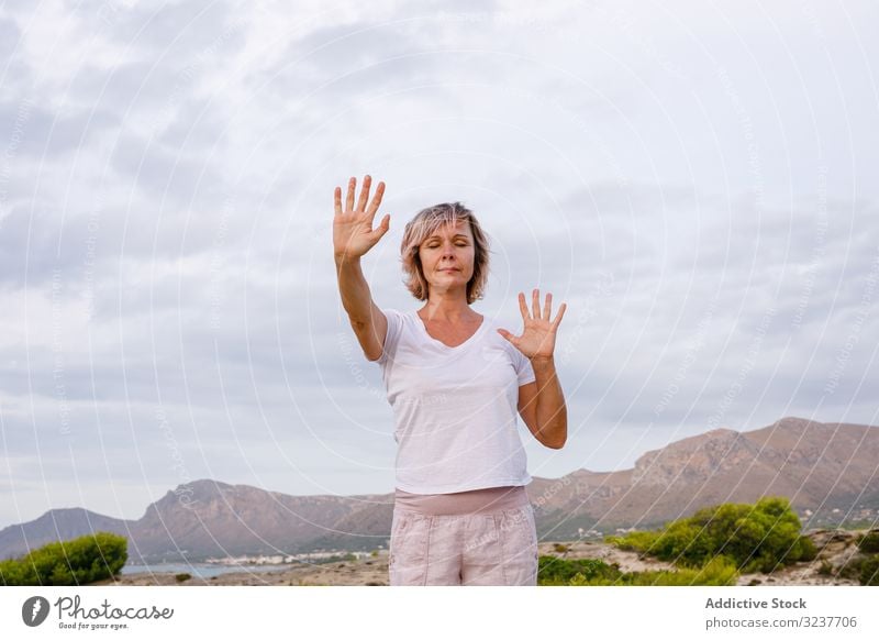 Erwachsene Frau bei einer Atemübung Übung Tai Chi geschlossene Augen Meditation Natur Himmel wolkig Training Erwachsener verschränkte Arme Gesundheit passen