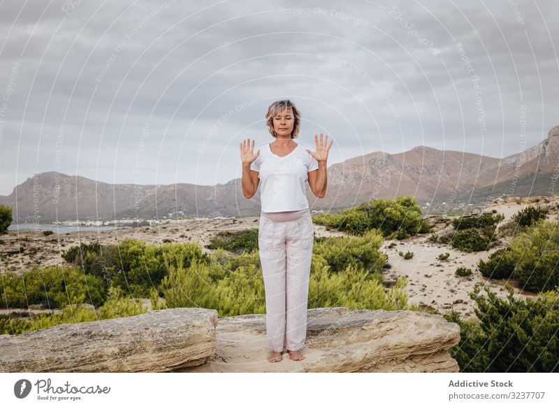 Barfüßige Frau meditiert auf Stein Meditation Übung Felsen Tai Chi geschlossene Augen Natur Himmel wolkig Training Erwachsener Barfuß Atem Gesundheit passen