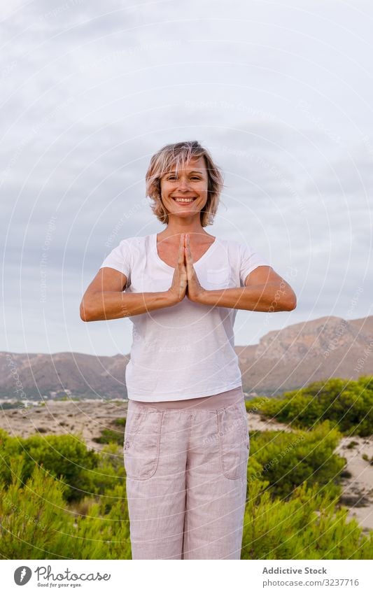 Barfüßige Frau meditiert auf Stein Meditation Übung Felsen Tai Chi umklammerte Hände Natur Himmel wolkig Training Erwachsener Barfuß Atem Gesundheit passen Yoga