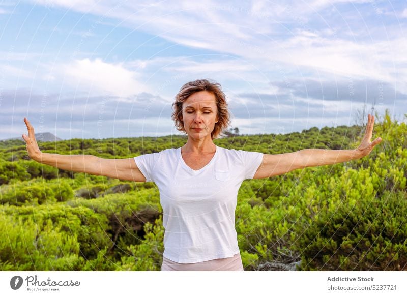 Erwachsene Frau praktiziert Kampfkünste in der Natur gestikulieren Übung Tai Chi geschlossene Augen Meditation Himmel wolkig Training Erwachsener Atem