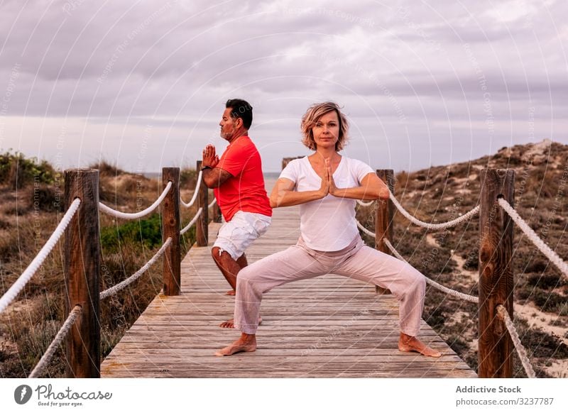 Erwachsenes Paar meditiert auf Holzpfad Meditation Weg Atem Übung Tai Chi umklammerte Hände Natur Himmel wolkig Training Frau Mann Erwachsener Gesundheit passen
