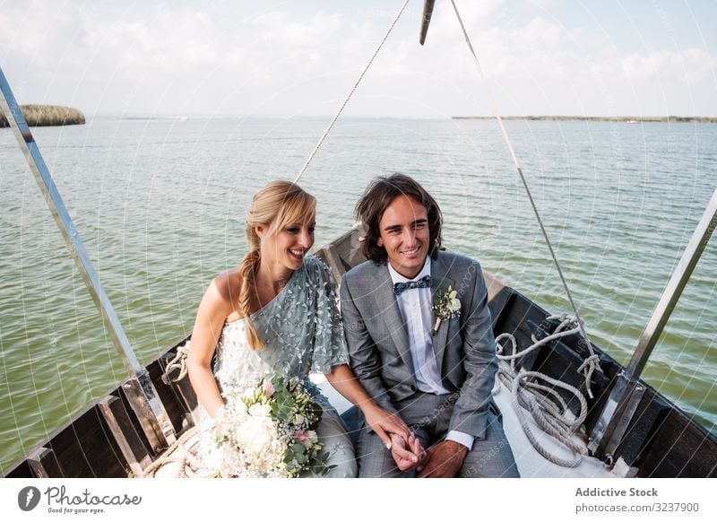 Paar hält sich beim Sitzen auf dem Boot an den Händen striegeln Braut Hochzeit Heirat Liebe Feier Ehefrau Frau Fröhlichkeit heiter umarmend Partnerschaft