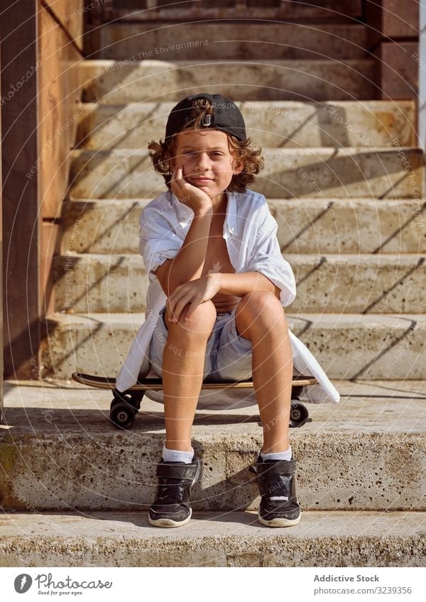 Kind sitzt auf einer Treppe im Skatepark Junge Skateboard Stil Sitzen heiter Glück Lifestyle Holzplatte ruhen auf die Hand gestützt Sport Freizeit Hobby jung