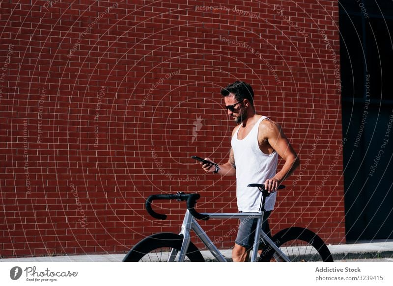 Sportlicher Mann mit Fahrrad beim Telefonieren stehen Handy benutzend modern sportlich aktiv Sommer männlich Sonnenbrille Radfahrer Smartphone Nachricht Texten