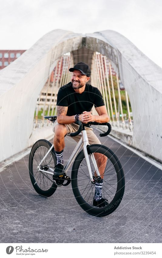 Fröhlicher Mann mit Fahrrad auf Steg stehend Großstadt Mitfahrgelegenheit Brücke modern aktiv sportlich Sommer männlich Erwachsener Glück heiter Lächeln