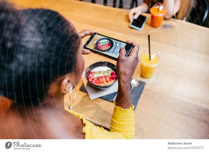 Frau beim Fotografieren von Lebensmitteln mit Smartphone fotografierend Smoothie Tisch Schalen & Schüsseln Saft Gesundheit Food-Fotografie Bild Afroamerikaner