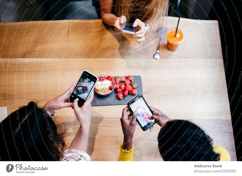 Frauen fotografieren gesundes Essen im Cafe fotografierend Lebensmittel Gesundheit Food-Fotografie Smoothie Erdbeeren Smartphone Tisch organisch