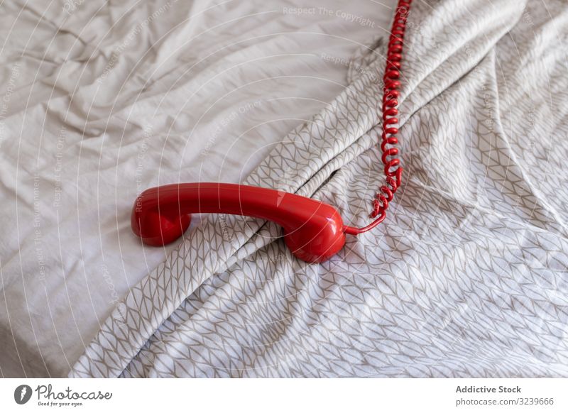 Roter Telefonhörer am Bett Mobilteil Draht rot retro heimwärts Komfort Anschluss weich altehrwürdig Anruf Mitteilung Bettdecke Schot Appartement flach klassisch