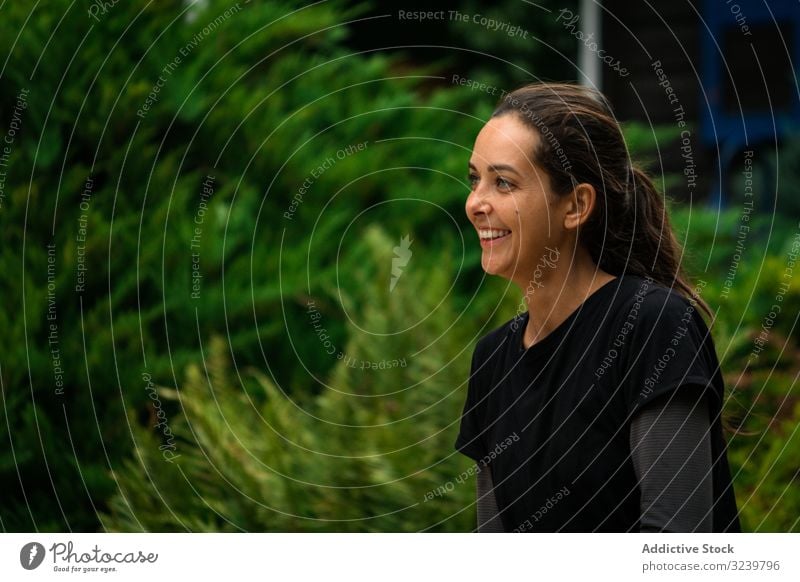 Fröhliche Frau ruht sich während des Trainings im Garten aus ruhen Lächeln Pause Sportbekleidung Buchse grün Fitness passen Gesundheit taiji rückzug Wellness