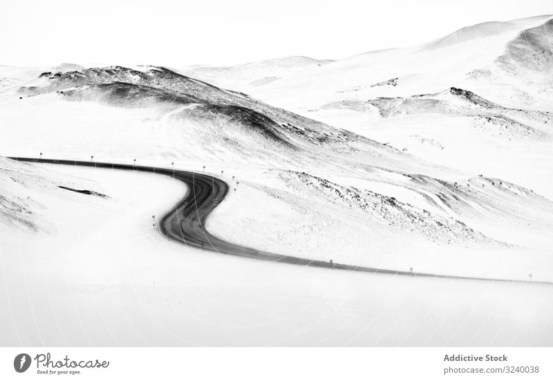 Kurvige Straße durch verschneite Hügel Schnee Winter weiß Island geschlängelt Landschaft Gelände Route kurvenreich Asphalt Weg Kamm Ambitus Berge u. Gebirge
