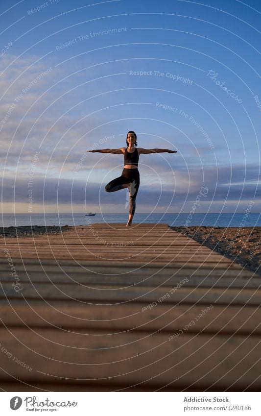 Fröhliche Frau macht Yoga an der Sandküste MEER Strand Asana Aktivität Baumhaltung Abend passen schlank Sportbekleidung Training Fitness Pose Gesundheit Übung
