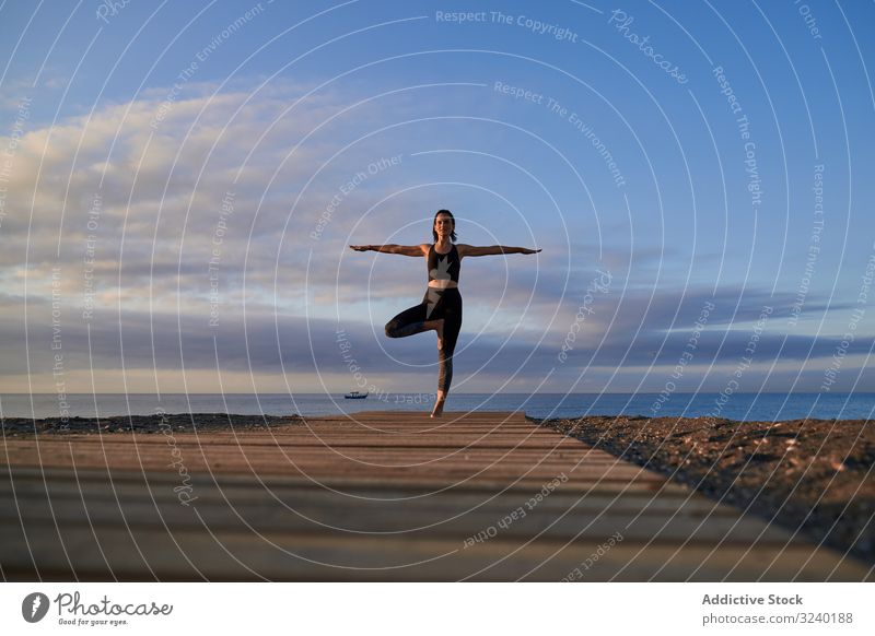 Fröhliche Frau macht Yoga an der Sandküste MEER Strand Asana Aktivität Baumhaltung Abend passen schlank Sportbekleidung Training Fitness Pose Gesundheit Übung