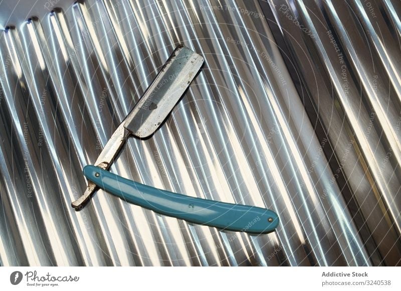 Messer eines Barbiers auf einer geriebenen Metallstruktur Design Mode Textur altehrwürdig antik Werkzeug Rasierer handgefertigt Haarschnitt Handel Friseur