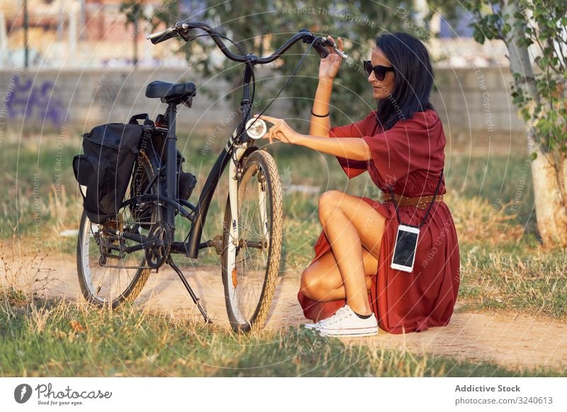 Frau repariert Fahrrad im Park fixieren Scheinwerfer Weg lässig Großstadt Sommer Aktivität Fahrzeug Reparatur ausrichten Verkehr Lifestyle ruhen