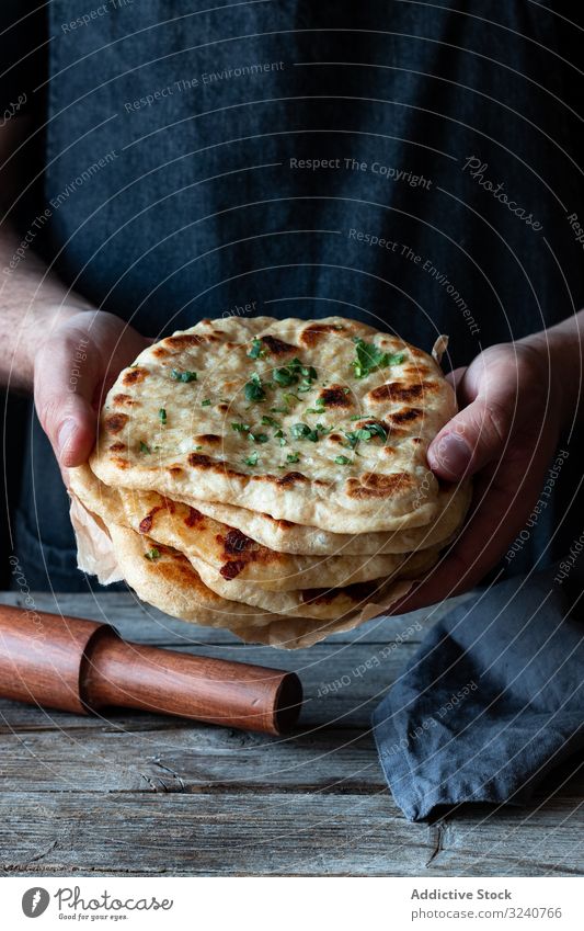 Erntehelfer demonstriert Naan-Brot Fladenbrot naan rustikal Mann zeigen Stapel frisch Lebensmittel Küche gekocht vorbereitet manifestieren männlich kulinarisch