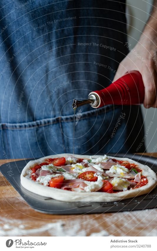 Pflanzenkoch giesst Öl auf Pizza Mann Erdöl eingießen Teigwaren Mehl weich Küchenchef frisch Vorbereitung Fleisch Lebensmittel Käse Tomate Schinken Saucen